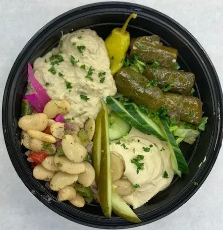 A black bowl filled with hummus beans and vegetables.