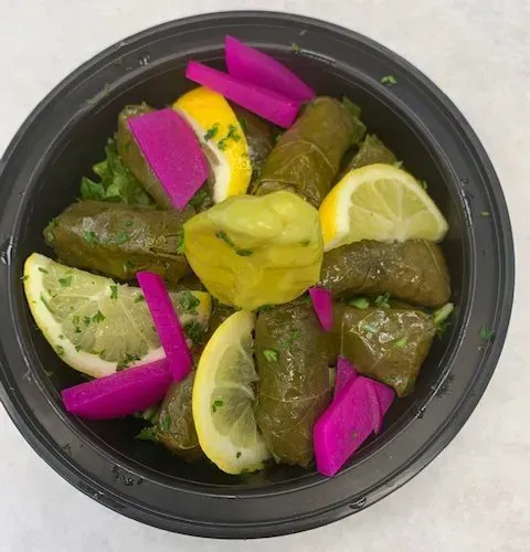 A black bowl filled with vegetables and lemon slices.