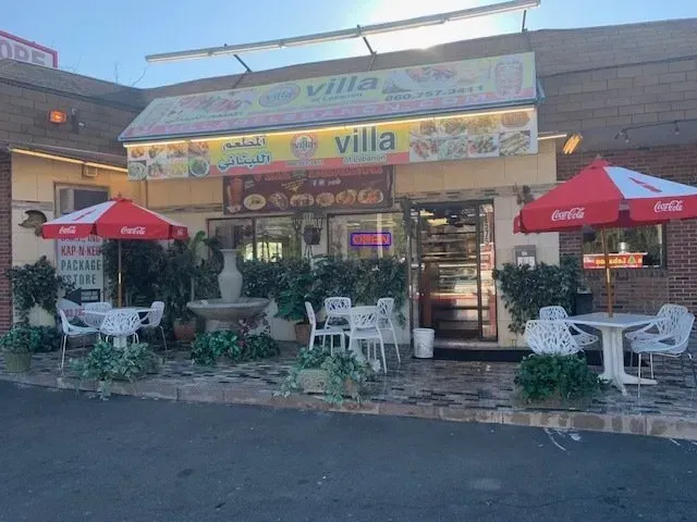 A restaurant with red and white umbrellas in front of it.