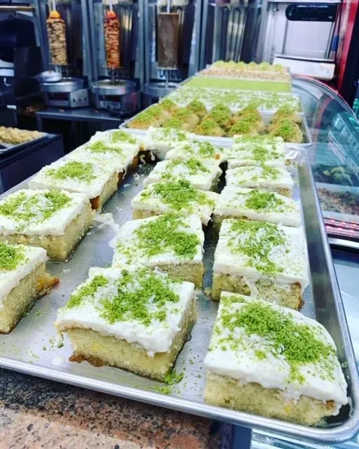 A tray of slices of cake with green sprinkles on top.