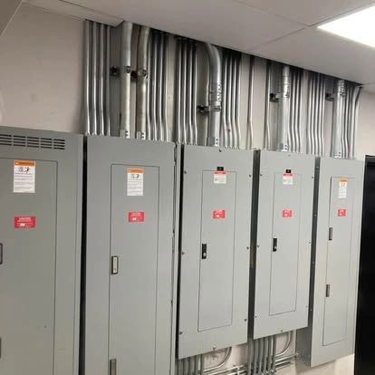 Electrical panels with metal conduit runs mounted on a wall.