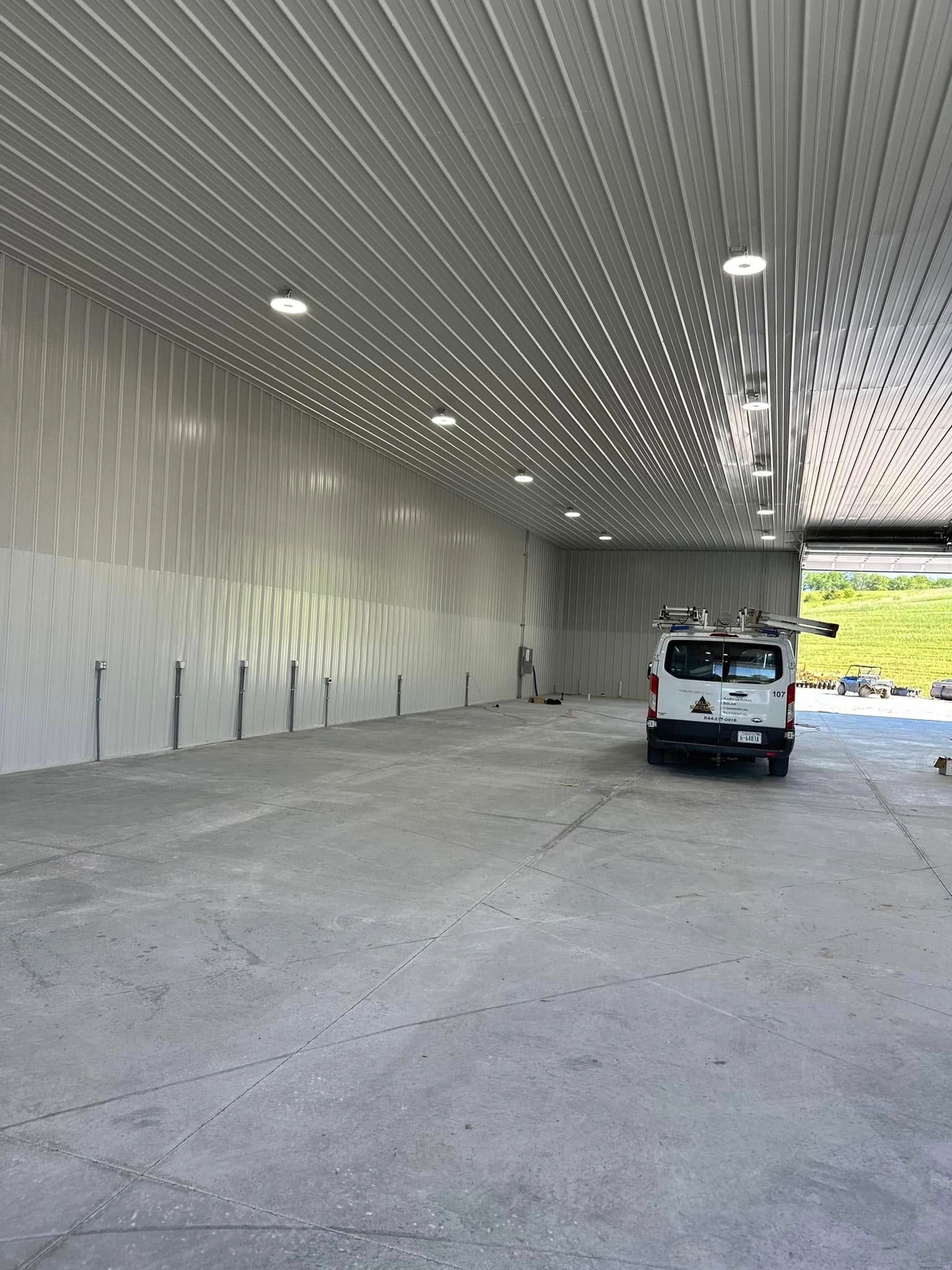 An empty, modern, white, concrete walled garage with a white van parked inside.