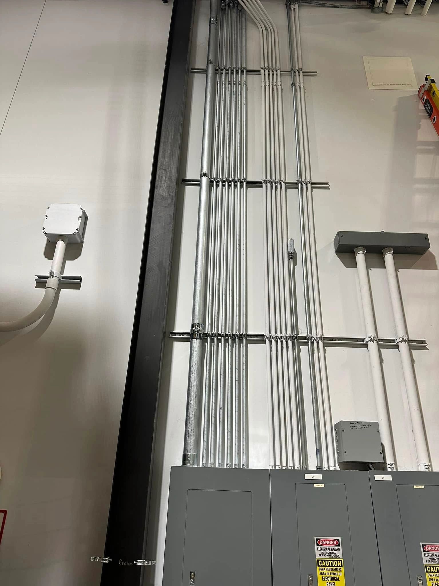 Electrical conduits and junction boxes on a wall. Gray metal pipes and boxes.