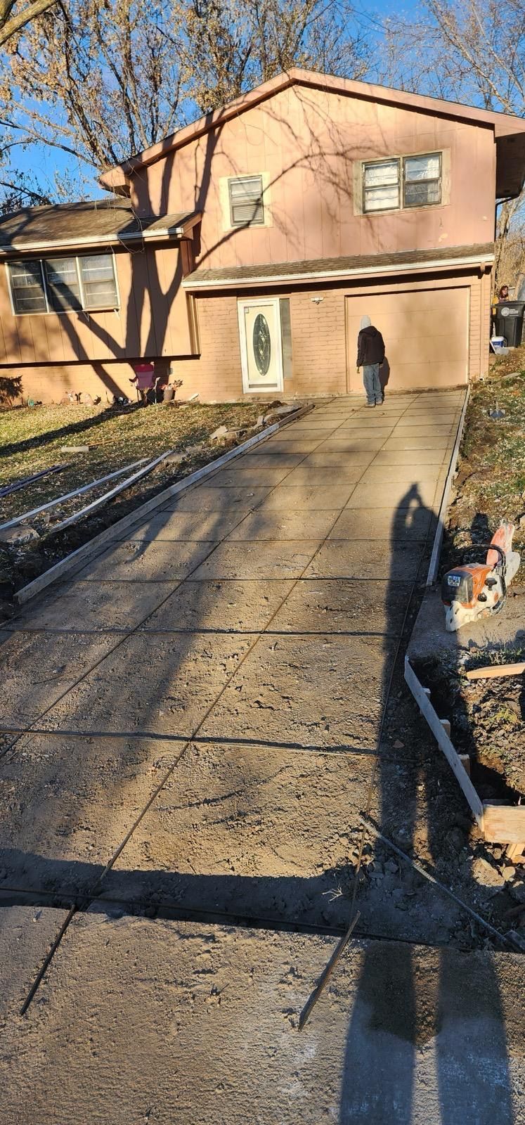 House with driveway and walkway in winter, with a person standing near the front door.