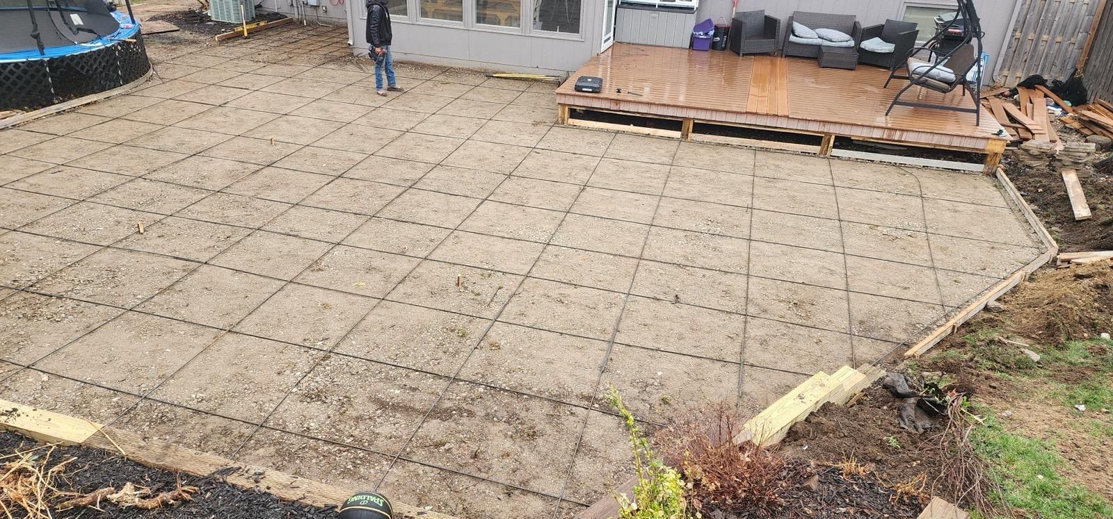 Gravel-covered patio area beside a house, with wooden steps and outdoor furniture on a deck.