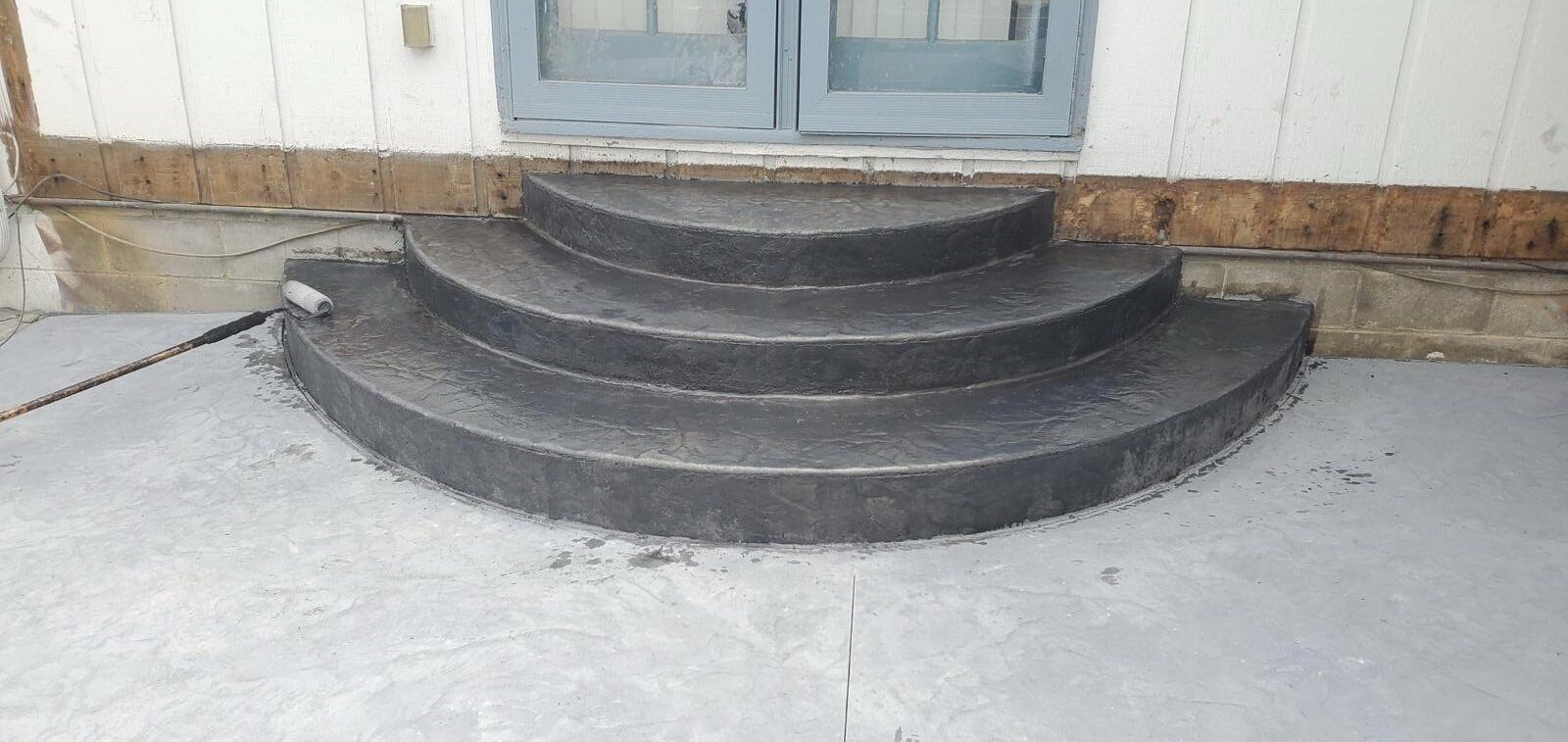Curved concrete steps leading to a blue doorway on a building exterior