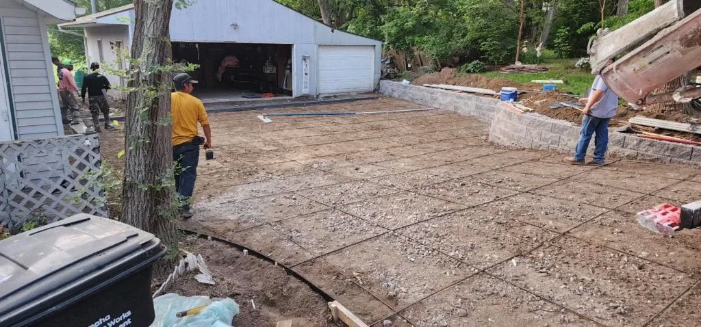 Construction site with gravel lot, workers, and a metal building in the background