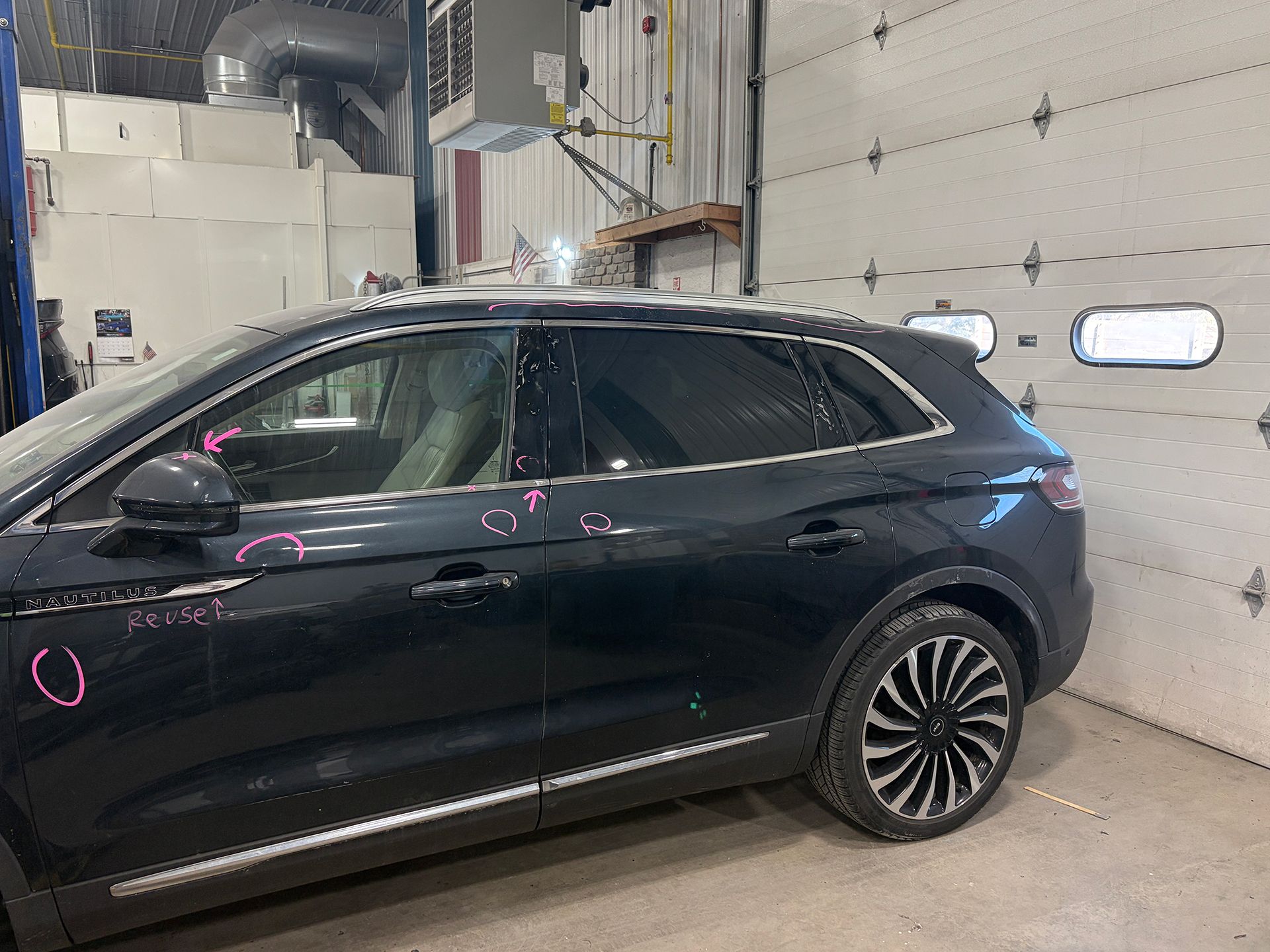 Black vehicle in a garage with repair marks
