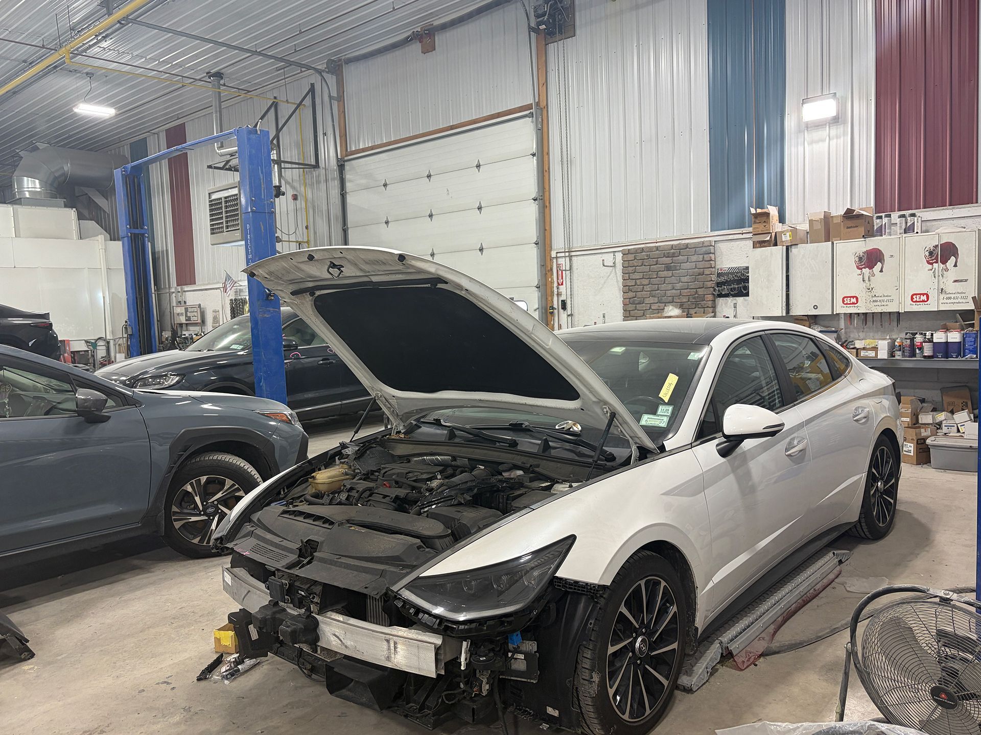 White sedan with open hood in an auto repair shop