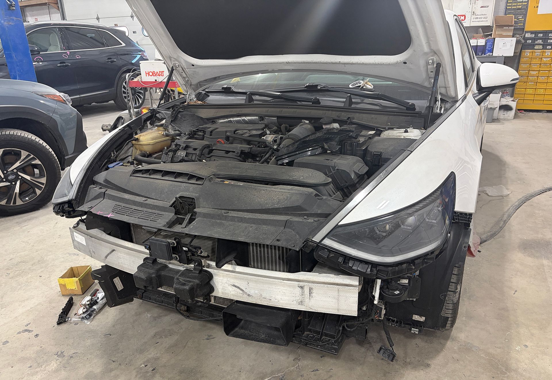 Damaged white car with front-end collision in a repair shop