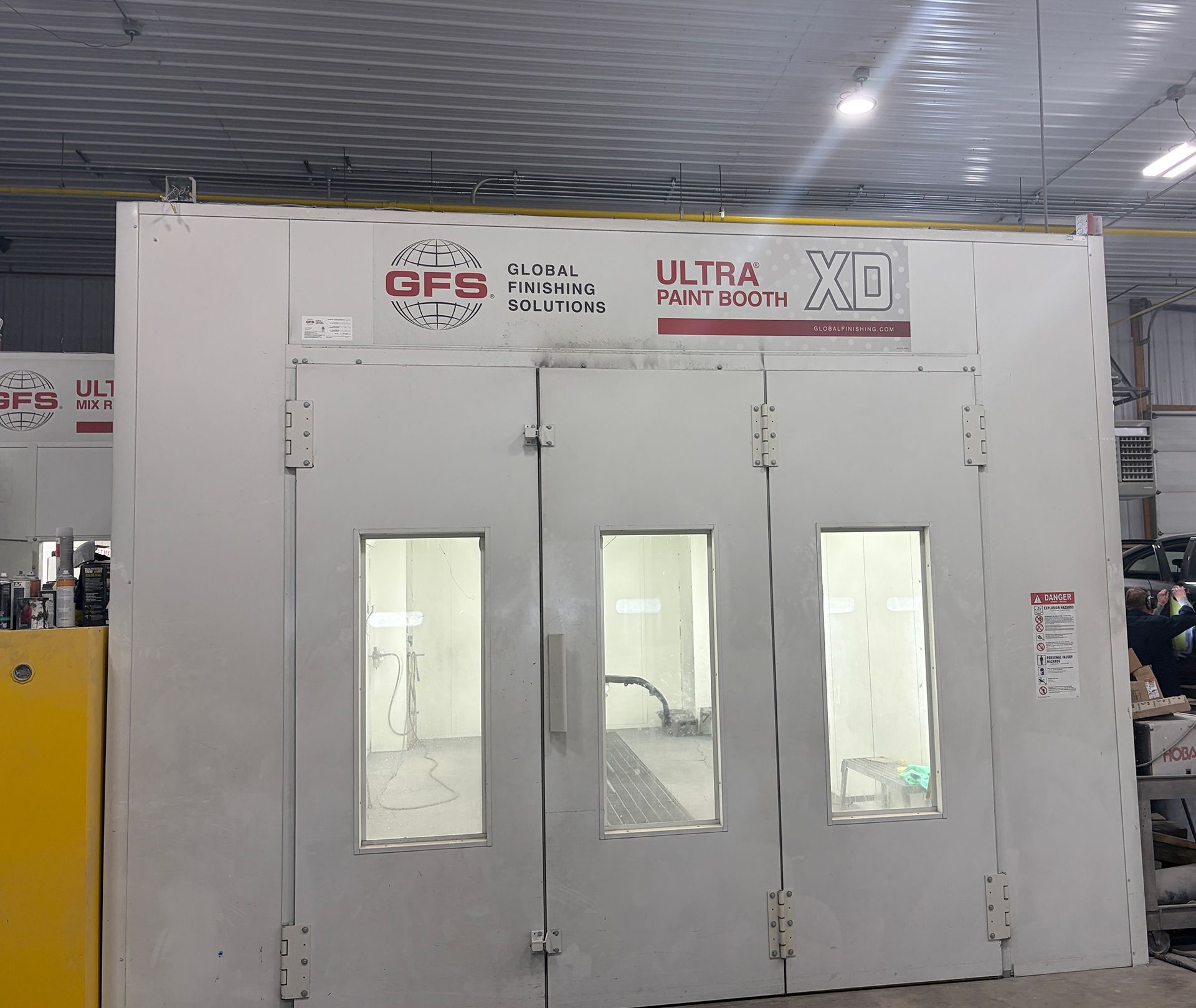 White industrial paint booth with double doors and narrow windows