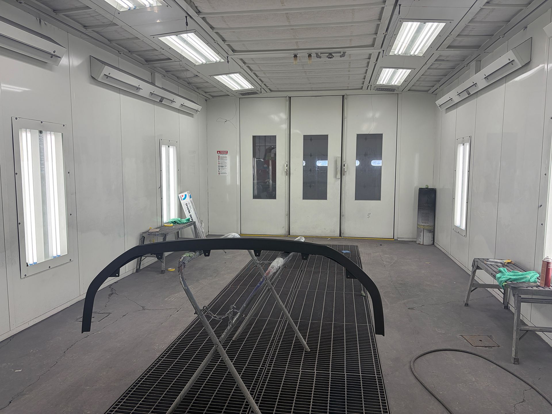 Spray paint booth interior with a partially painted car body