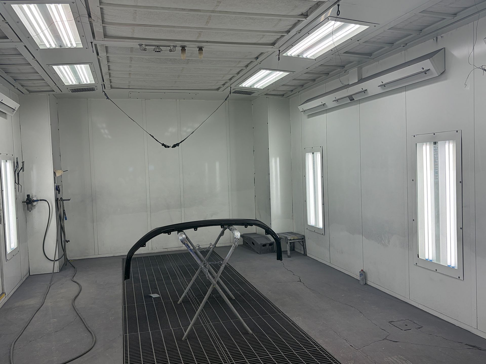 Spray-paint booth with fluorescent lights and a metal rack in the center