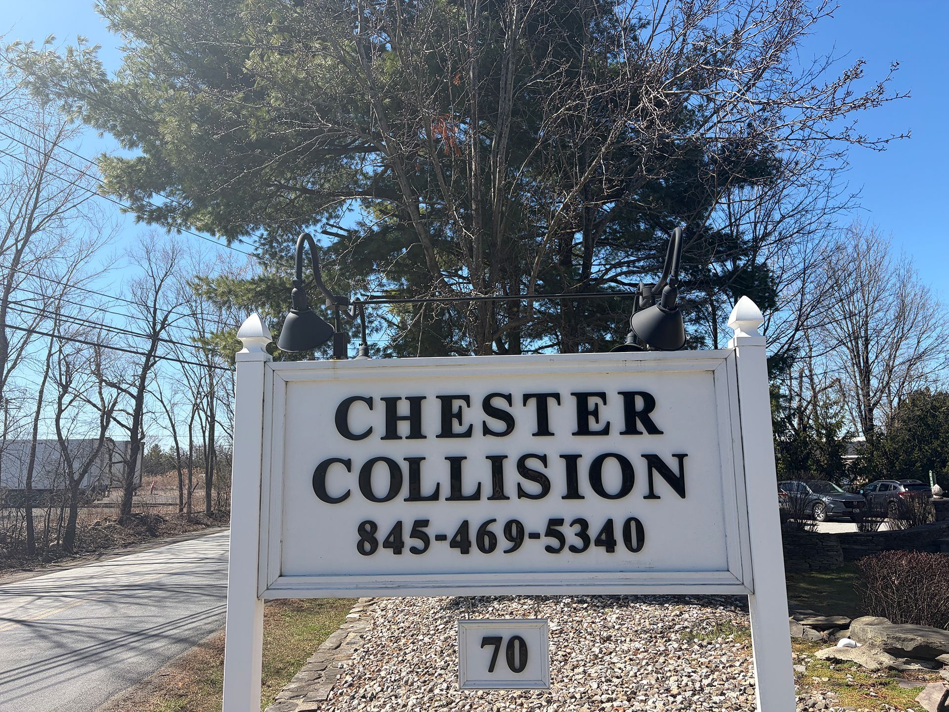 Chester Collision Inc's road sign with trees behind it