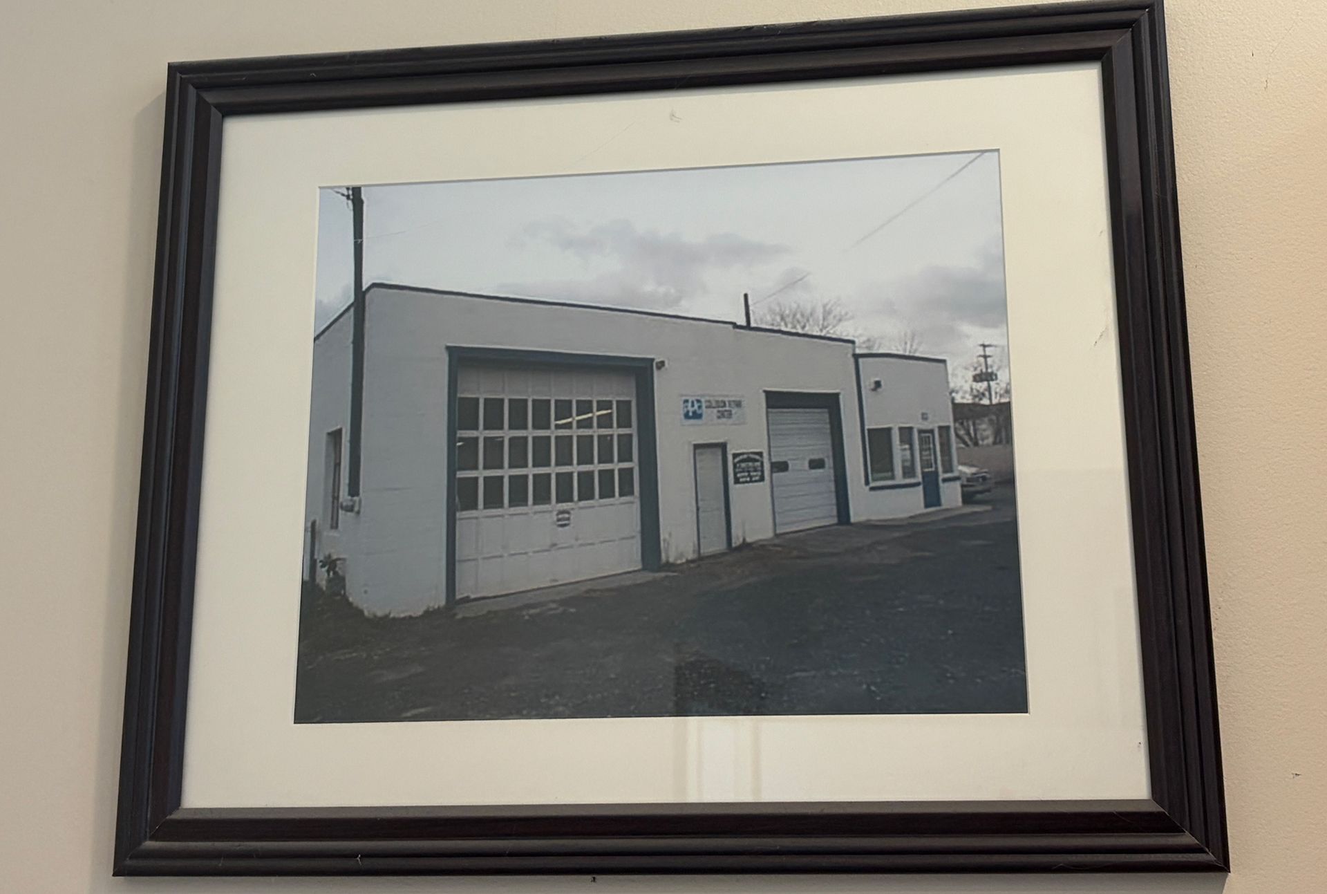Framed photo of a white industrial building with garage doors and a paved lot
