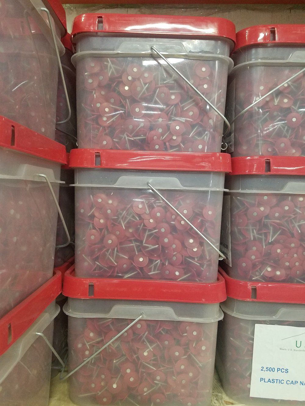 Red-lidded plastic buckets stacked with red cherries.