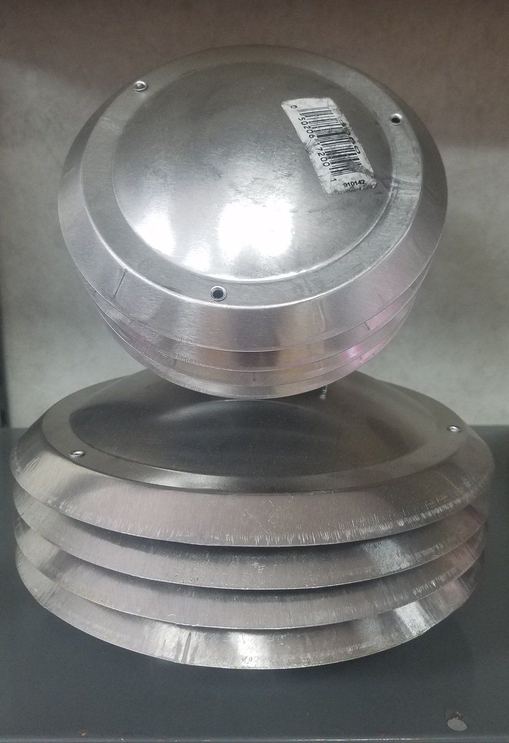 Stack of silver metal discs topped with a large, round metal object; a label is visible.