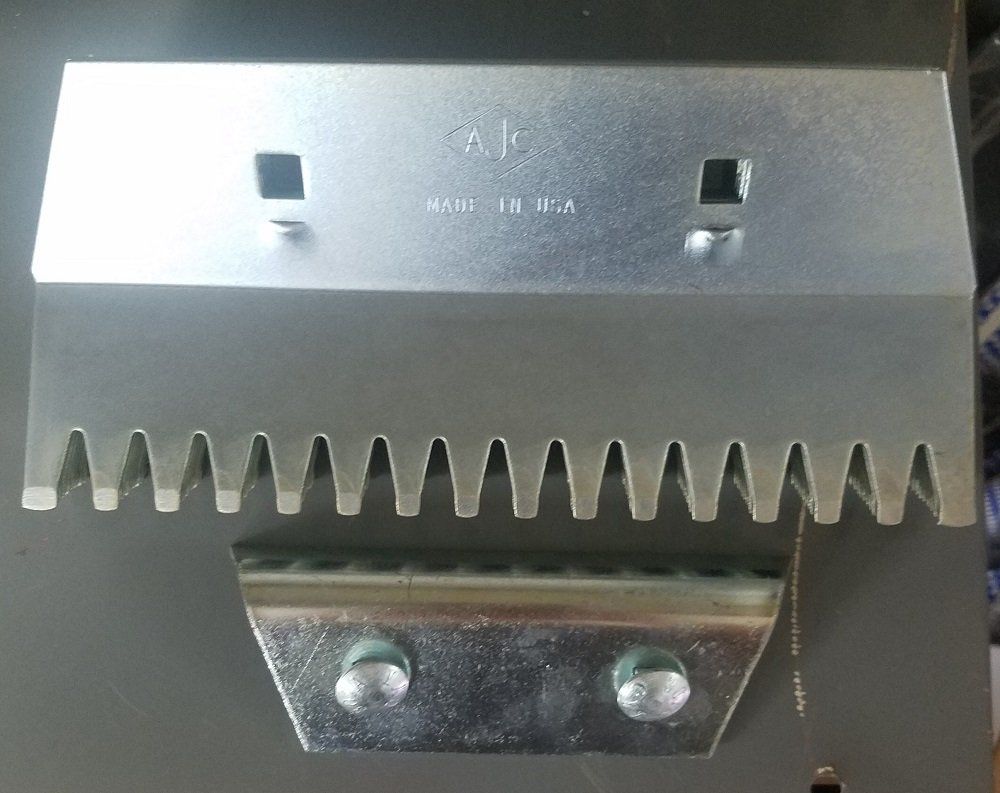A silver metal tool with teeth and two square holes, along with a smaller bracket, likely for industrial use.
