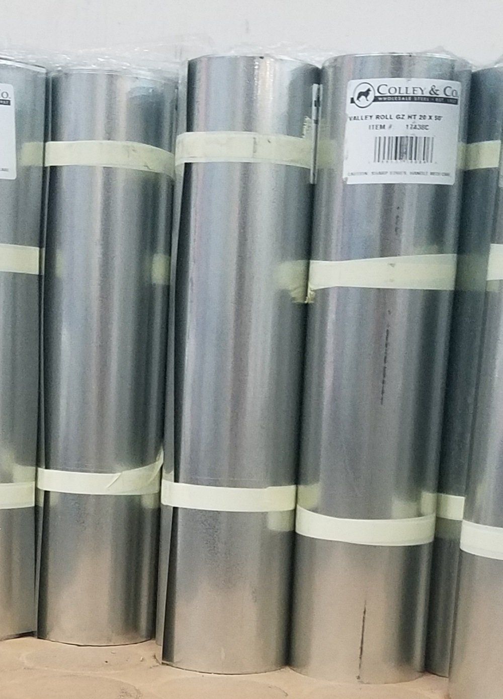 Rolled metal sheets, bound with tape. Stacks of silver material.