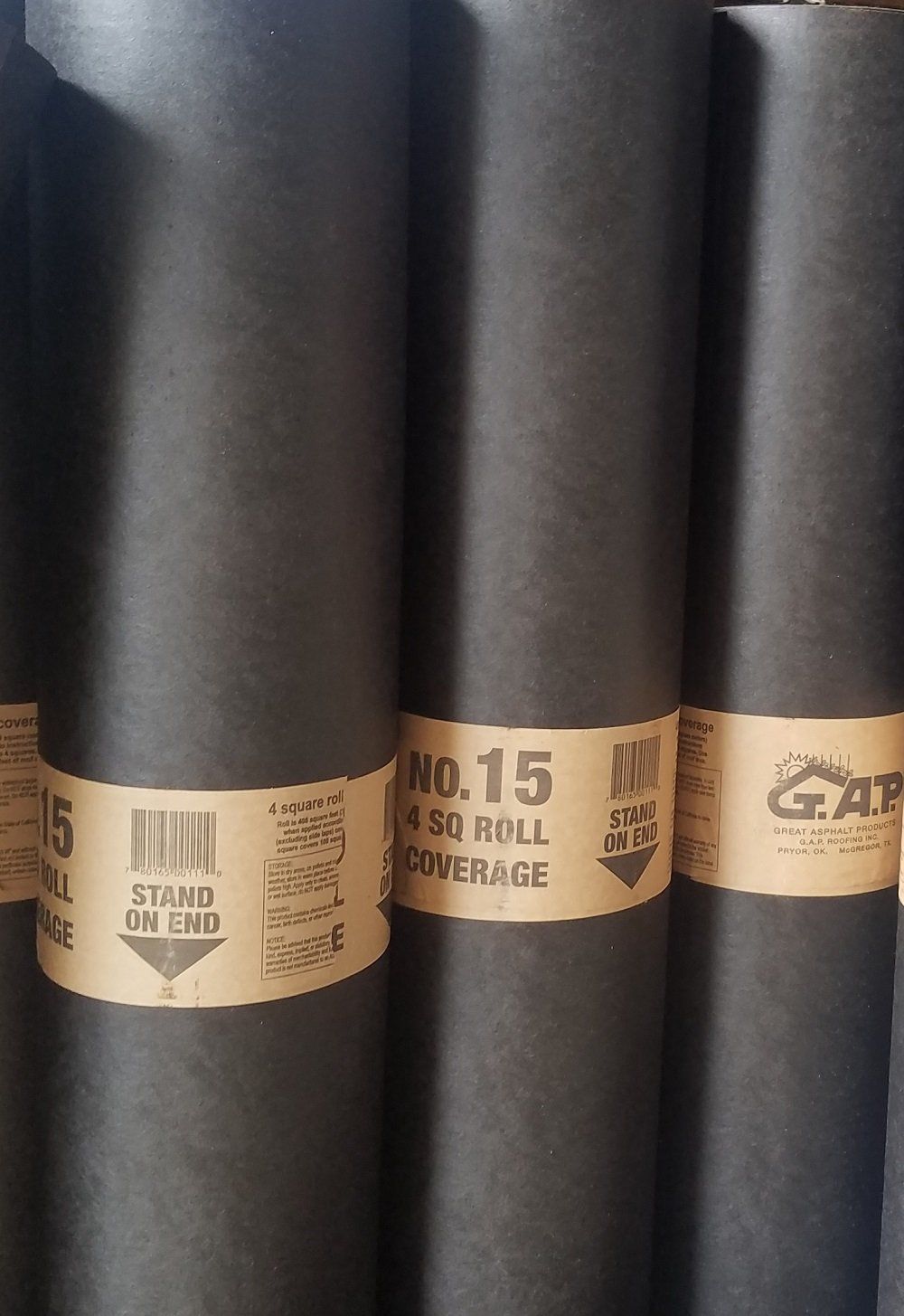 Black rolls of roofing felt with product labels.
