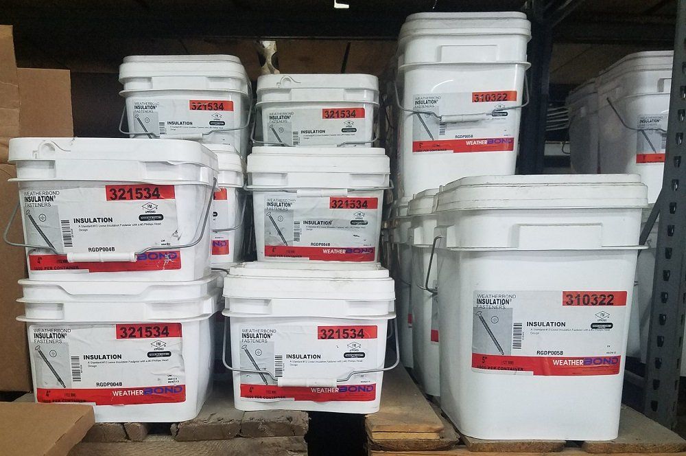 White buckets stacked on shelves, labeled with text and barcodes.