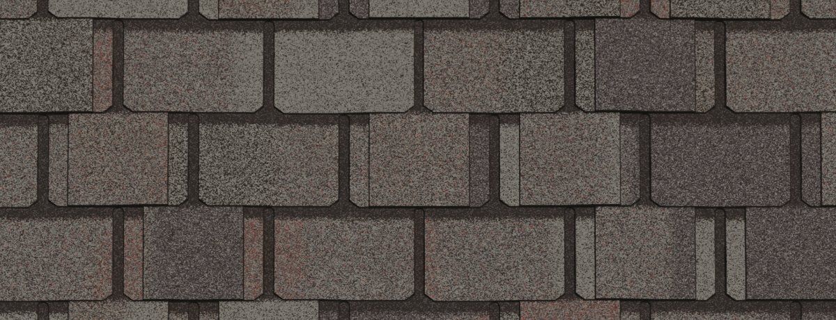 Close-up of brown and gray asphalt roofing shingles arranged in a staggered pattern.