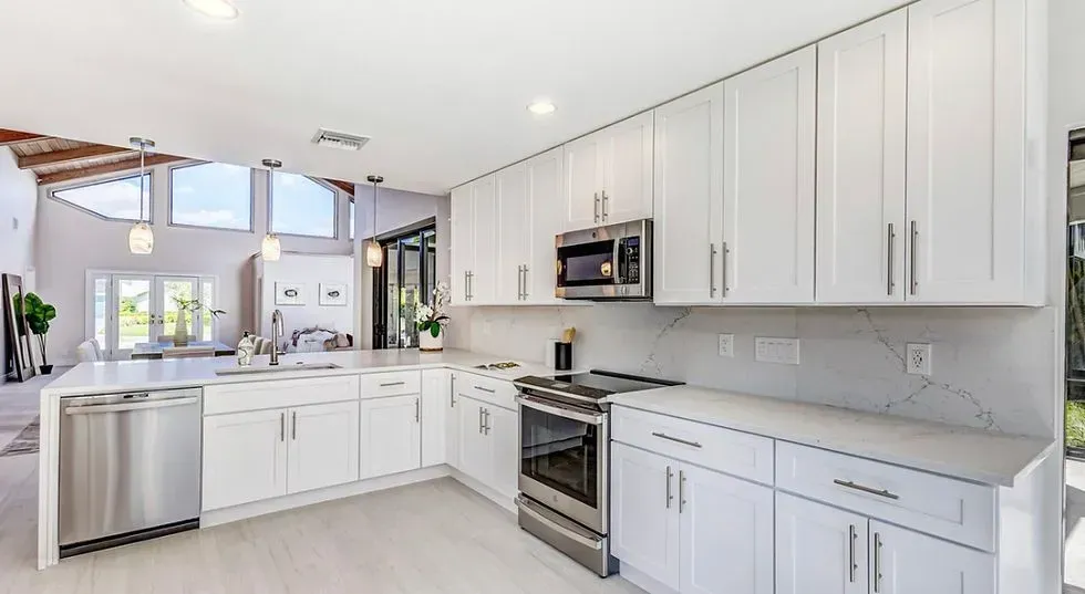 Bright modern white kitchen with island, stainless appliances, and vaulted ceiling