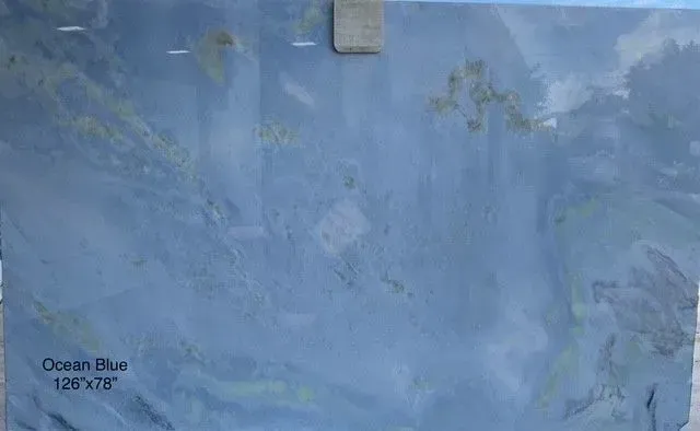 Ocean blue painted wall with a subtle cloud-like texture and a small paint label in the lower left.