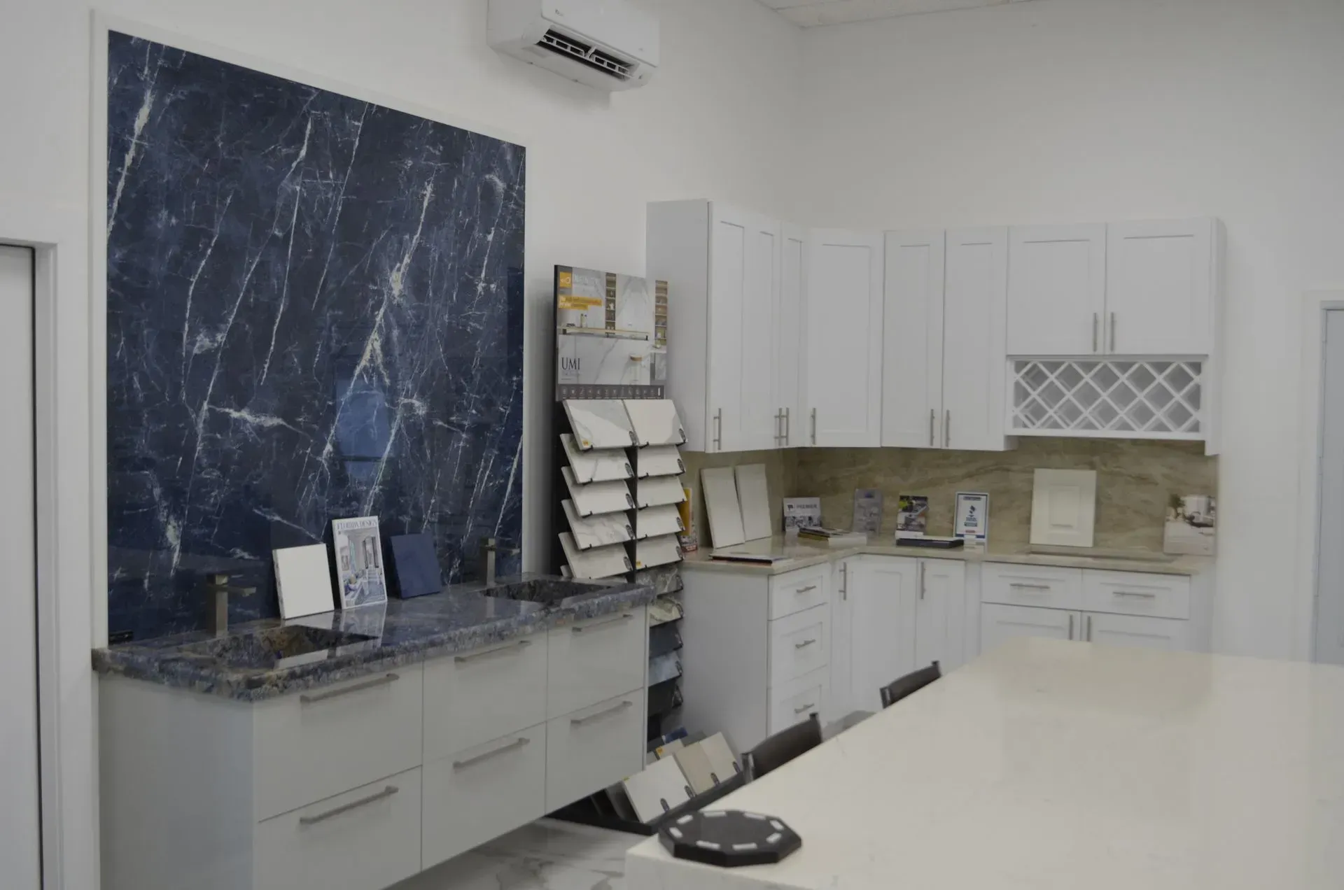 Modern white kitchen with marble island, dark blue backsplash, and white cabinets