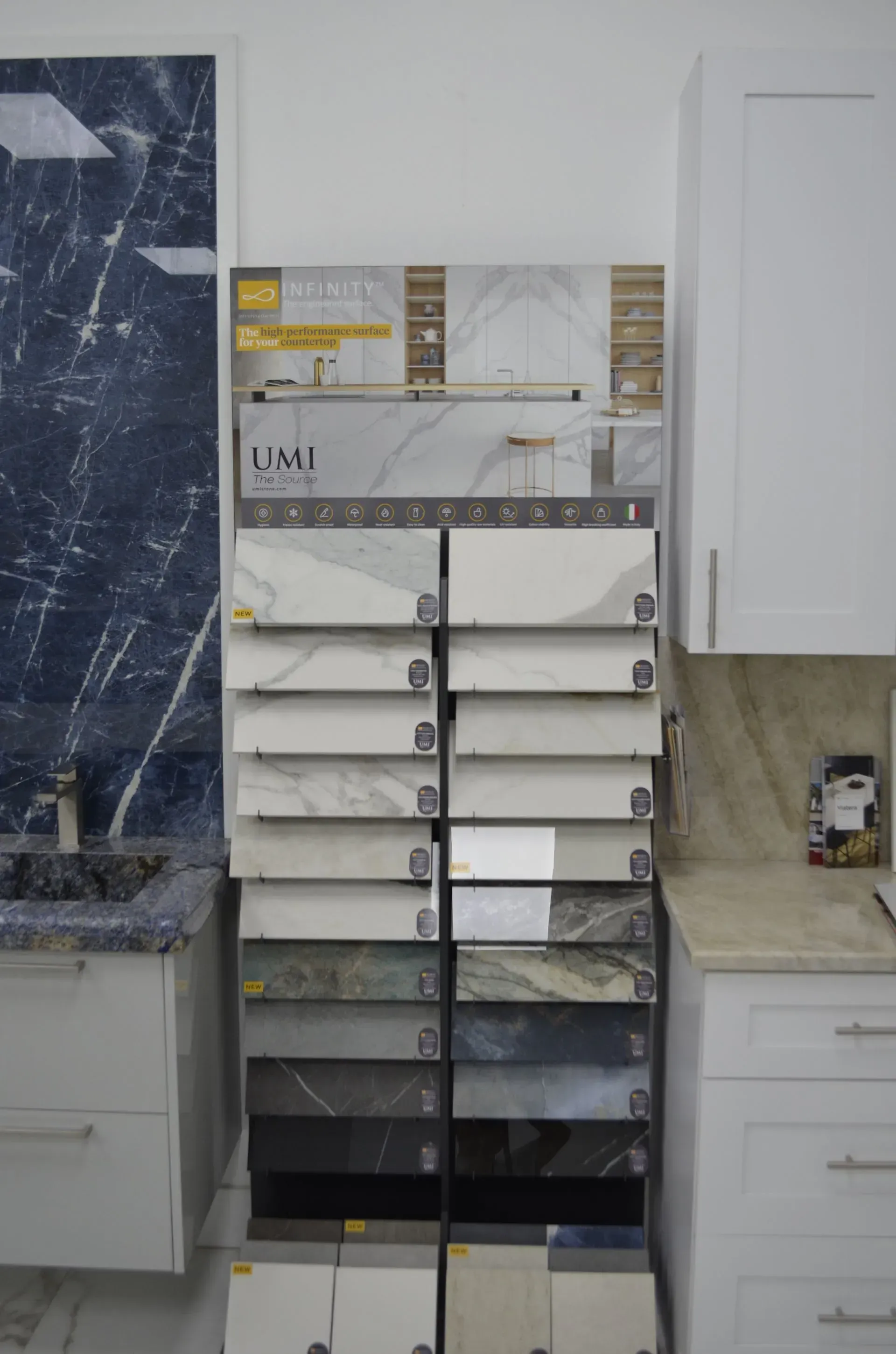 Slanted tile display rack in a kitchen remodel, with white cabinets and a dark blue backsplash sample on the left
