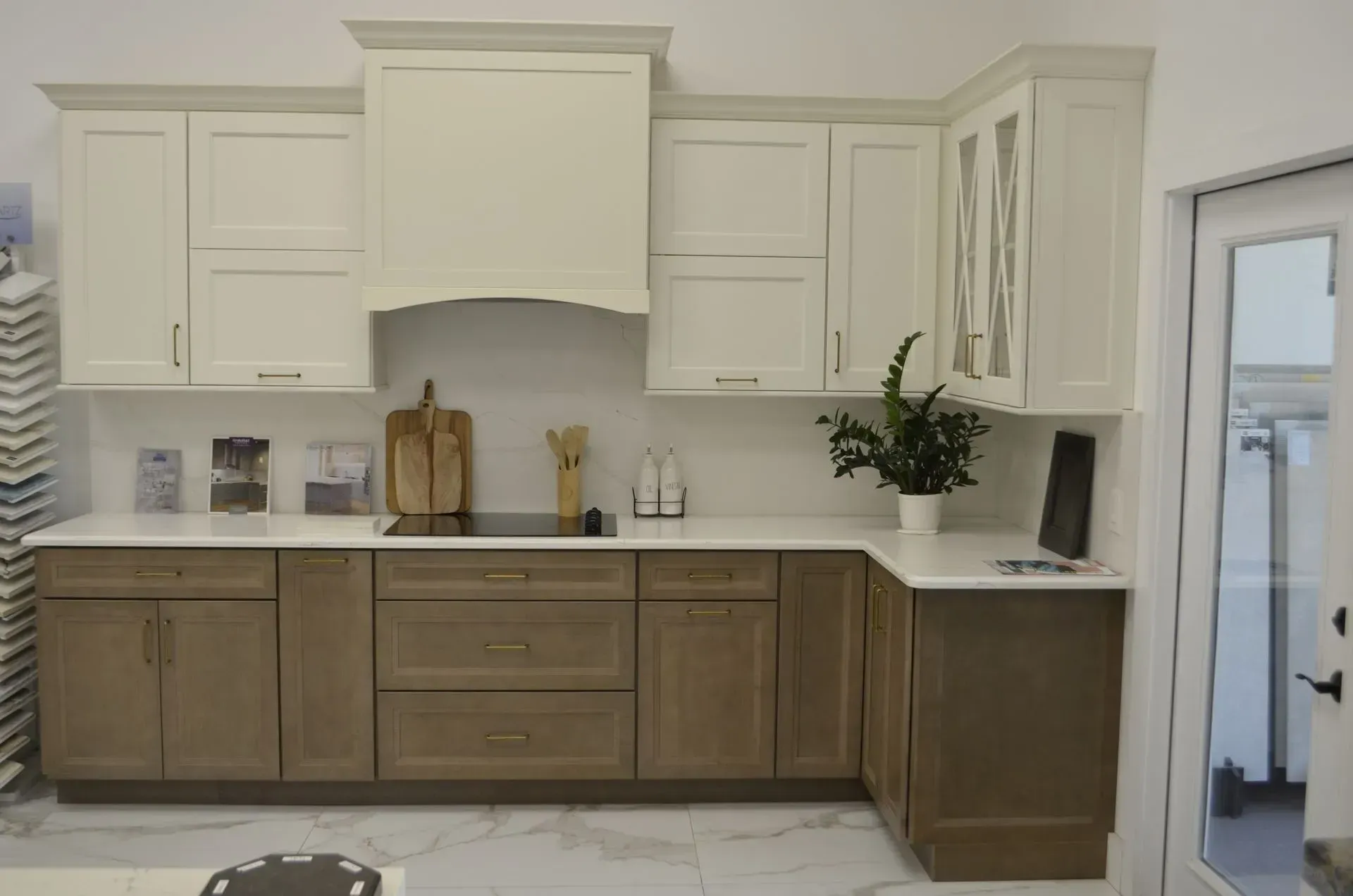 White and wood kitchen cabinets with a white countertop, range hood, and a vase of flowers on the right.