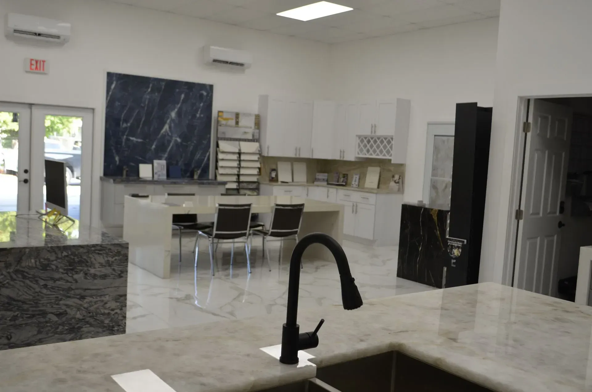 Bright kitchen with white cabinets, black countertops, and a central island with a black faucet.
