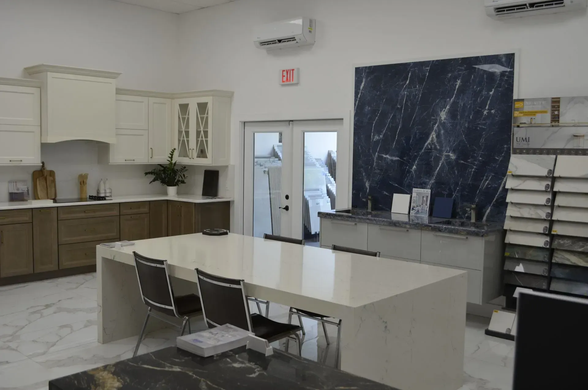 A clean classroom kitchen with cabinets, tables, chairs, and a large blackboard on the wall.