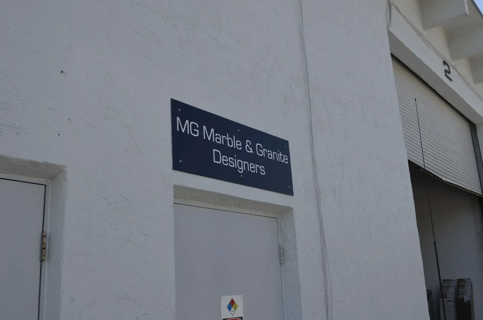 White building wall with a dark sign above a door reading “M&S Master & B. S. Designers.”