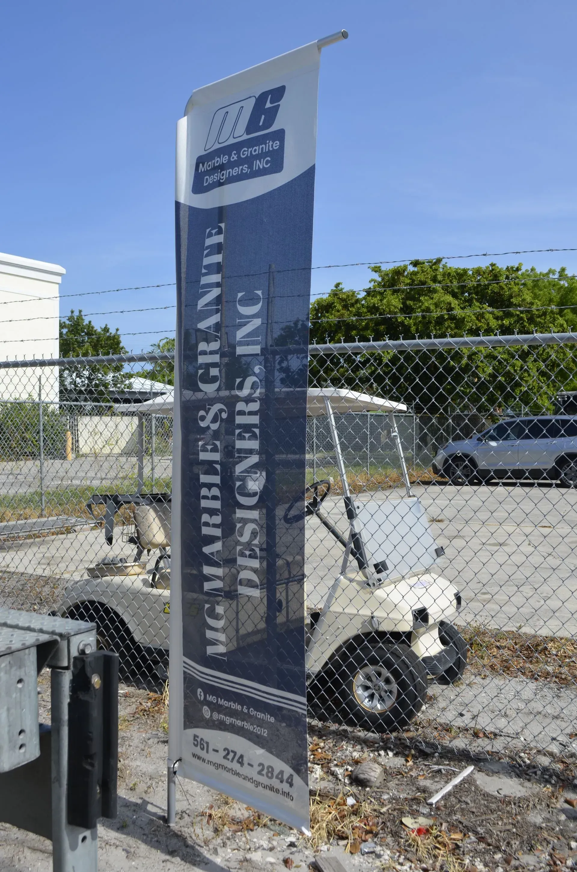Blue event banner on a fence in a parking lot under a clear sky