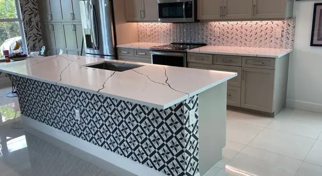 Modern kitchen with white island, patterned tile base, and gray cabinets and backsplash