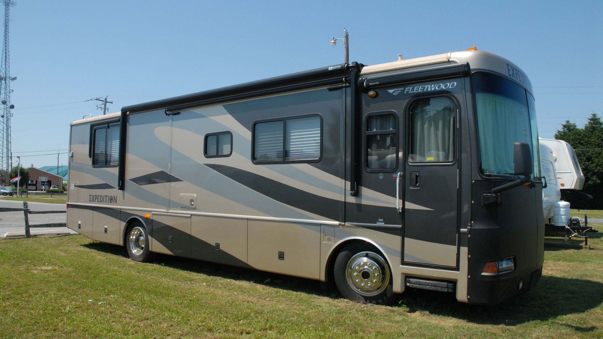 A large rv is parked in a grassy field.