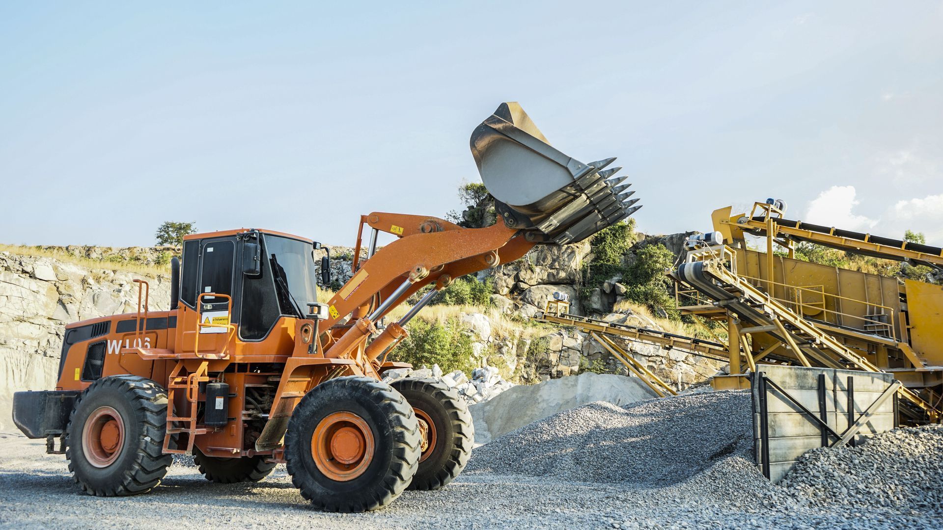 A bulldozer is loading rocks into a pile in a quarry.