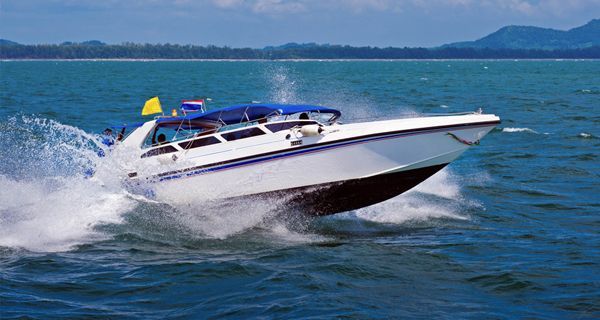 A white and blue speed boat is floating on top of a body of water.