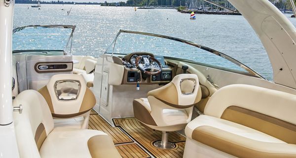 The inside of a boat with a wooden deck and a steering wheel.