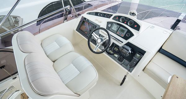 The cockpit of a boat with a steering wheel and two seats.