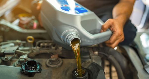 A man is pouring oil into a car engine.