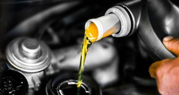 A person is pouring oil into a car engine.