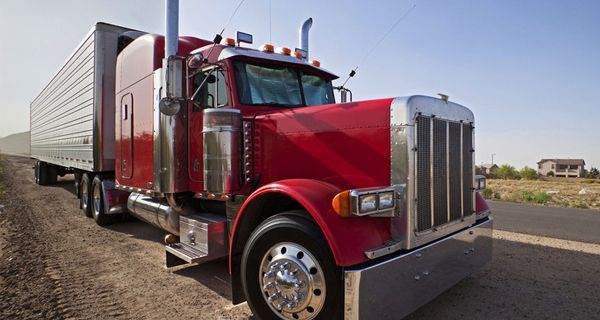 A red semi truck is parked on the side of the road.