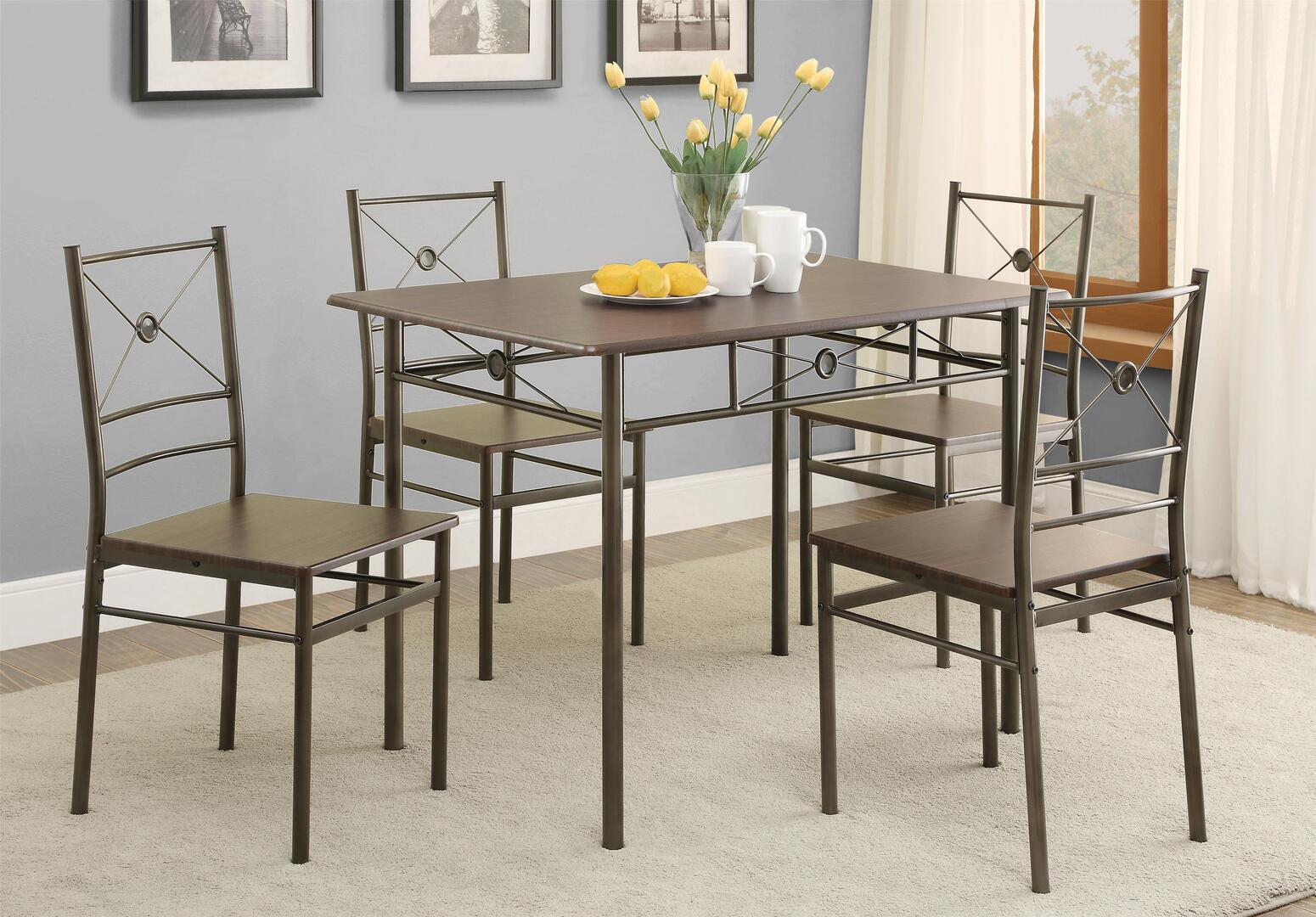 A dining room table with four chairs and a vase of flowers on it