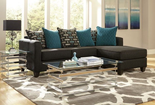 A living room with a black sectional couch and blue pillows