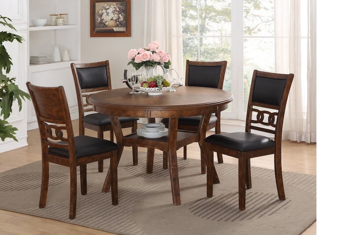 A dining room table with four chairs and a vase of flowers on it.