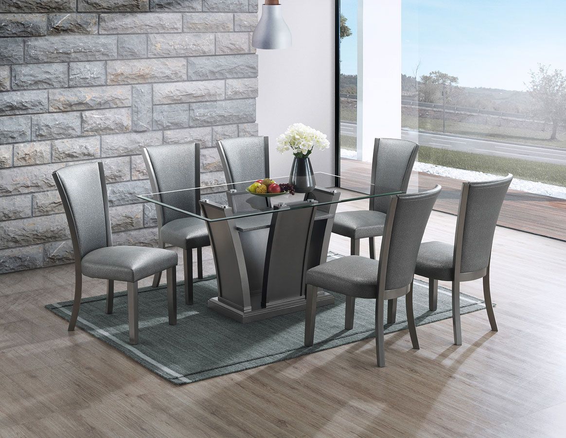 A dining room table and chairs are sitting on a rug in front of a brick wall.