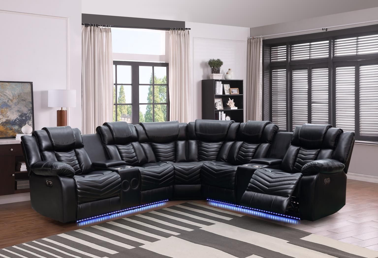 A living room with a black sectional couch and a rug.