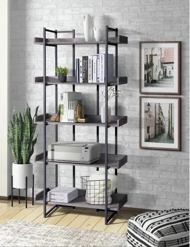 A bookshelf is sitting in a living room next to a brick wall.